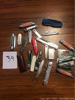 Top-down image of all 22 pocket knives and multi-tools arranged on wooden surface.