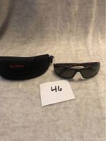 Bolle sunglasses paired with their soft case, set against a plain background, with a small label showing lot number 46.