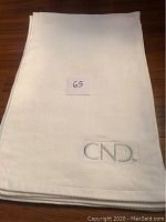 Stack of white hand towels showing the embroidered CND logo on top towel.