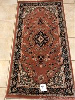 Photo showing the full carpet on a tiled floor, displaying its size, shape and pattern.