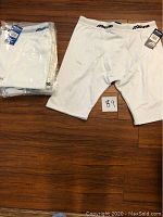 One photo showing one white Mizuno boxer brief size XXL outside plastic packaging alongside four pairs in the original plastic packaging.