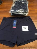 Navy blue Mizuno volleyball shorts with tags, size XXL, laid out flat and stacked in plastic packaging