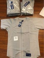Six Mizuno baseball shirts packaged in plastic shown together, gray color, with tags attached.