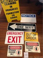 Photo showing all seven safety signs displayed on a floor, different shapes and colors, clear text for various safety, directional, and warning messages.
