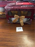 Photo of a boxed Godiva coffee mug gift set featuring two white ceramic mugs and Godiva chocolates inside a red box with decorative white patterns and a gold Godiva ribbon tied in front.