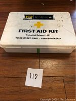 Closed white plastic First Aid Kit box with K-D Supply Braeasco branding and yellow cross