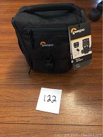 Front view of black Lowepro Nova 140 AW II camera bag with logo and attached tag visible.