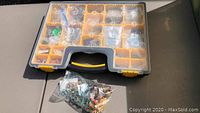 Plastic organizer case with multiple compartments filled with glass pendants, partially closed lid.
