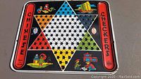 Full view of vintage tin Chinese checkers board showing colorful hexagram and Chinese-themed illustrations