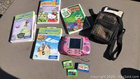 Complete set including pink Leapster console, 6 game cartridges, and black carrying case on table