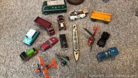 Photo shows entire lot of 15 small diecast vehicles including cars, trucks, train engine, airplane, and ship models.