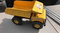 Full side view of the yellow Nylint Jumbo dump truck on a table outdoors.
