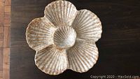 Top view of the ceramic serving platter shaped like a flower with sea shell petals, showing beige and brown glazed surface.