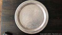 Top view of silver tray on dark surface, showing clean upper side and ornate edge