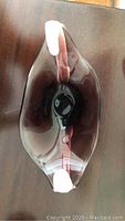 Top view of the oval blown glass bowl with dark purple tint and white enhancements on edges.
