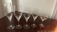 Side view of 5 different styles of etched stemware glasses ranging from flute to shorter glasses