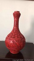 Full front view of one red cinnabar lacquer vase showing slender neck and bulbous body.