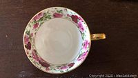 Top view of porcelain tea cup showing floral pattern inside rim and gold handle