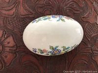 Top view of white porcelain egg with hand-painted blue, pink, and yellow floral pattern.