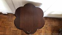 Top view showing the flower-shaped solid mahogany table top with visible marks and stains.