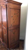 Side view of armoire showing floral painted vine motif on side panel