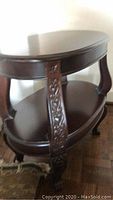 Overall view of two-tier oval side table showing shape and carved legs