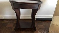 Front view of solid mahogany side table showing curved legs and lower shelf.