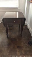 Front view of solid mahogany side table with drawers and turned legs, top leaves retracted.