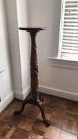 Full view of mahogany pedestal table against wall showing overall design and tripod base