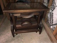 Side view of the dark mahogany wood side table showing curved magazine holder and glass top.