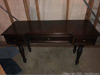 Front view of full desk showing three drawers and turned legs