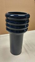 Side angle view showing the ribbed neck and smooth cylindrical body in deep blue glaze.