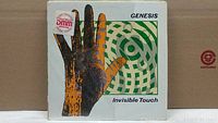 Close-up of Genesis Invisible Touch vinyl album cover with hand print and circular design