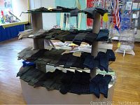 Five-tier display of folded dress sock pairs in black, navy and grey on store shelving.