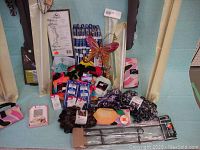 Lot laid out on blue sheet with curtain rods, knitting needles, socks, ribbons, garden décor butterfly, garden skewers and bags visible.