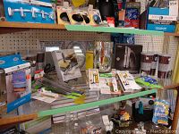 Shelves with various kitchen and decor items including tumblers, bottle openers, kitchen utensils, large candle holder, and picture frames