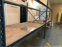 Front angle view showing full length of blue steel shelving with plywood shelves