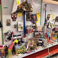 Overview of toys, vehicles, socks, mops, and other items arranged on a shelf with pegboard background
