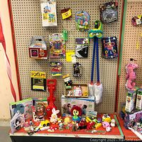 Wide shot of assorted toys including string art kits on pegboard and various toys arranged on red shelf