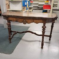 Front view of vintage oval folding console table with carved legs and oval top.
