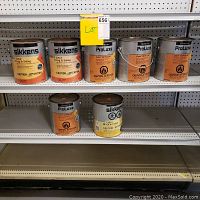 Seven cans of Sikkens Cetol brand wood finish paint arranged on store shelving. Mix of Cetol Log & Siding, ProLuxe Cetol 23 Plus RE and Cetol DEK Finish.