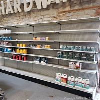 Four metal shelving units installed side by side with shelves in place and pegboard backs visible