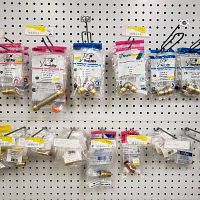 Pegboard display of packaged SharkBite brass fittings mounted on hooks