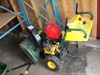 Overview of snow blower showing green chassis, yellow engine housing, red gas tank, black chute and wheels