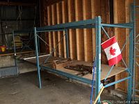 Full-length view of blue steel shelving rack with plywood shelves and Canadian flag attached