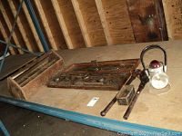 Wide view of the lot items on a wooden surface including tap and die set, wooden toolbox, hand planer, and emergency light.