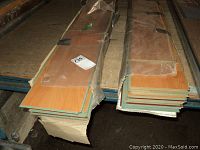 Three cases of laminate flooring on shelf, two partially open with boards visible, one sealed case.