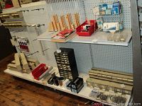 Wall shelving with nine plastic storage bins holding screws, rivets, washers, grommets, flag holders, impellers and more