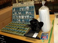 Photo of entire lot showing black boat propeller, white fender wrapped in plastic, weatherproof registration letters in plastic trays, and retail bracket kits.
