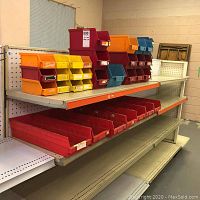 Shelf loaded with small orange and yellow bins on top, medium red bins stacked behind, large red bins below